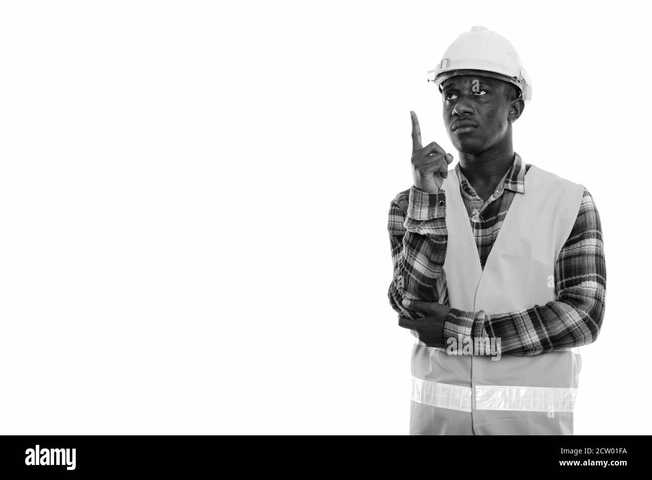 Studio shot von jungen schwarzen afrikanischen Mann Bauarbeiter zu denken, während Finger nach oben zeigen Stockfoto