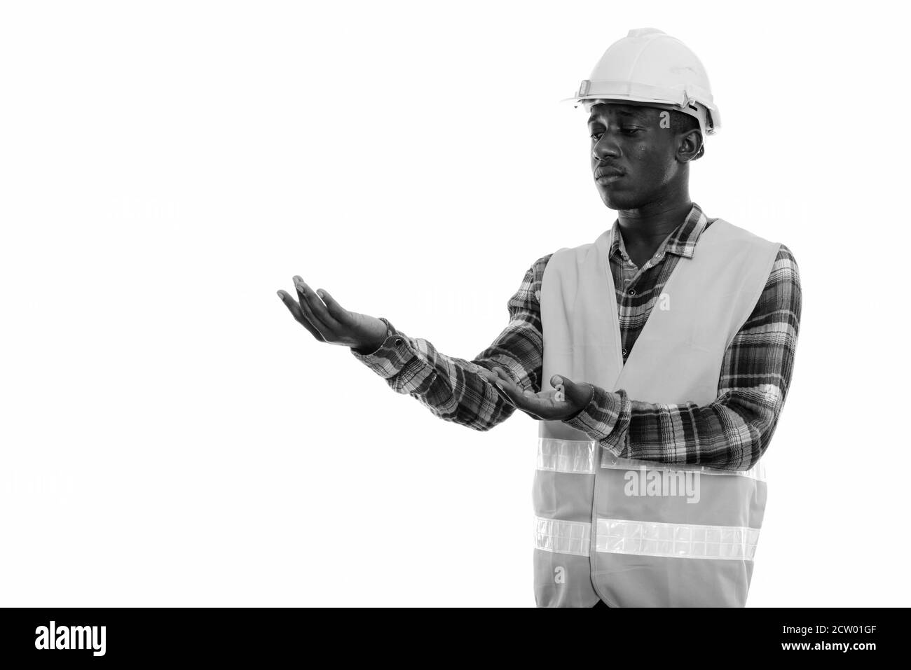 Studio shot von jungen schwarzen afrikanischen Mann Bauarbeiter etwas angezeigt Stockfoto