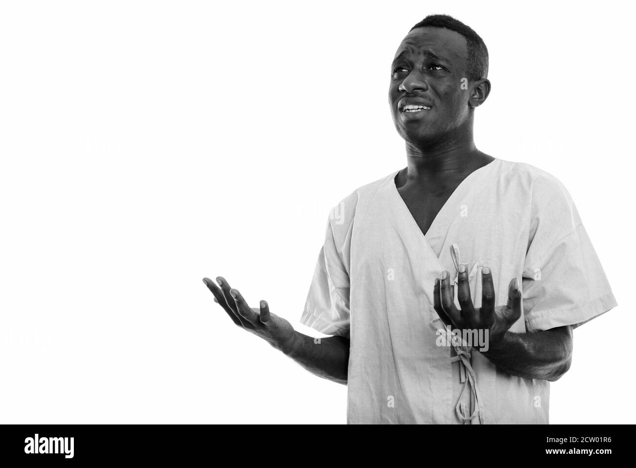 Studio shot von jungen schwarzen afrikanischen Mann Patienten denken, während Sie traurig und heben beide Arme Stockfoto