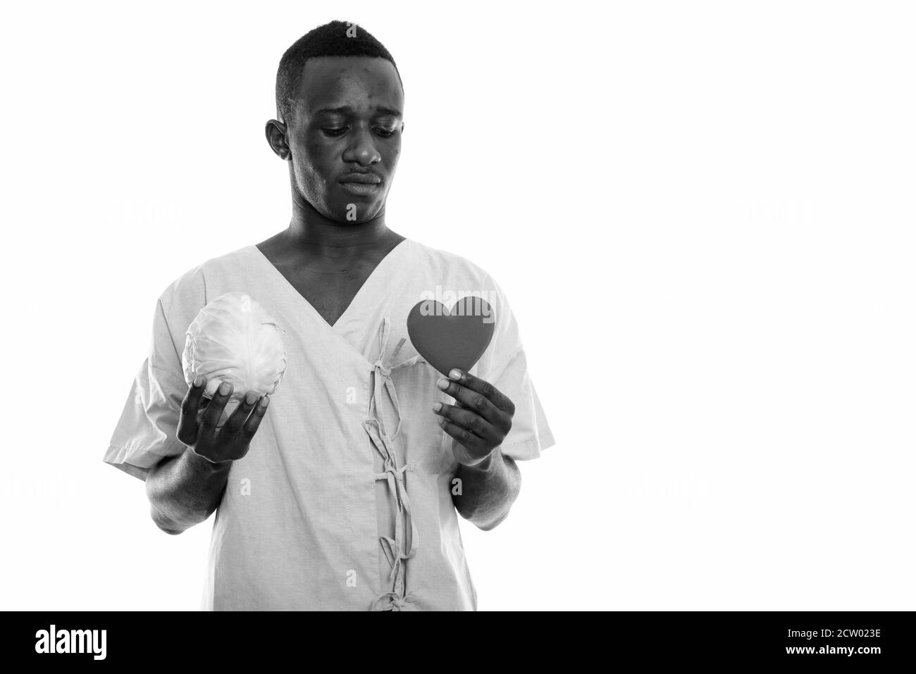 Studio Schuss von jungen schwarzen afrikanischen Mann Patient hält Kohl Und Blick ins Herz Stockfoto