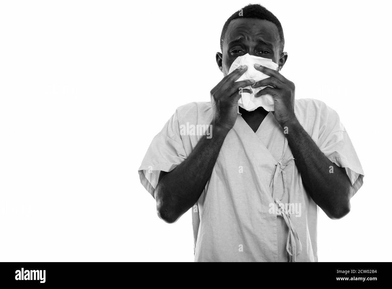 Studio shot von jungen schwarzen afrikanischen Mann Patient suchen Kranken während seine Nase weht mit Gewebe Stockfoto