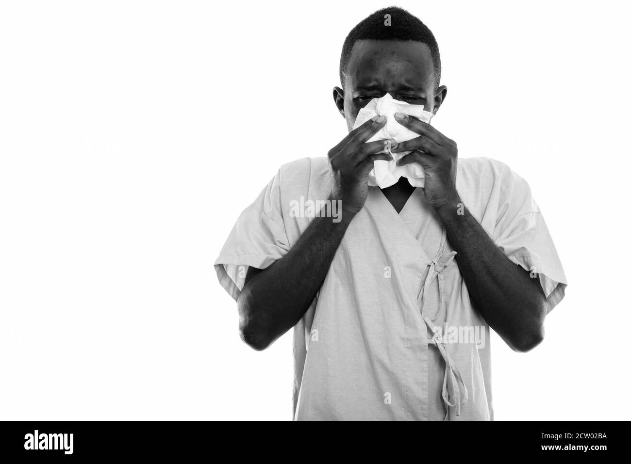 Studio shot von jungen schwarzen afrikanischen Mann Patient seine Nase weht mit Gewebe Stockfoto