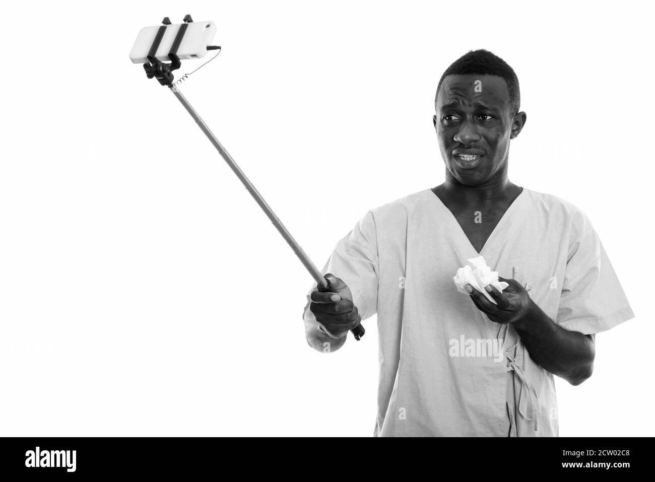 Junger afrikanischer Mann Patient nimmt Selfie-Bild mit Handy Auf Selfie-Stick, während das Gewebe gehalten wird Stockfoto Junger afrikanischer Mann Patient nimmt Selfie-Bild mit Handy Auf Selfie-Stick, während das Gewebe gehalten wird Stockfoto