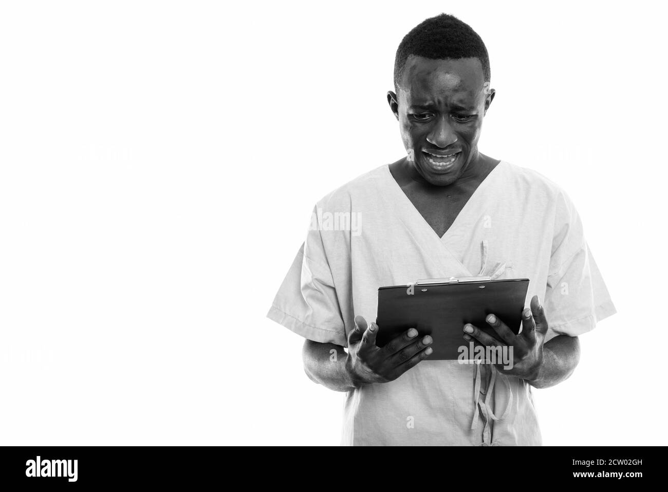 Studio shot der Jungen traurigen schwarzen afrikanischen Mann Patienten auf Zwischenablage während geschockt Stockfoto