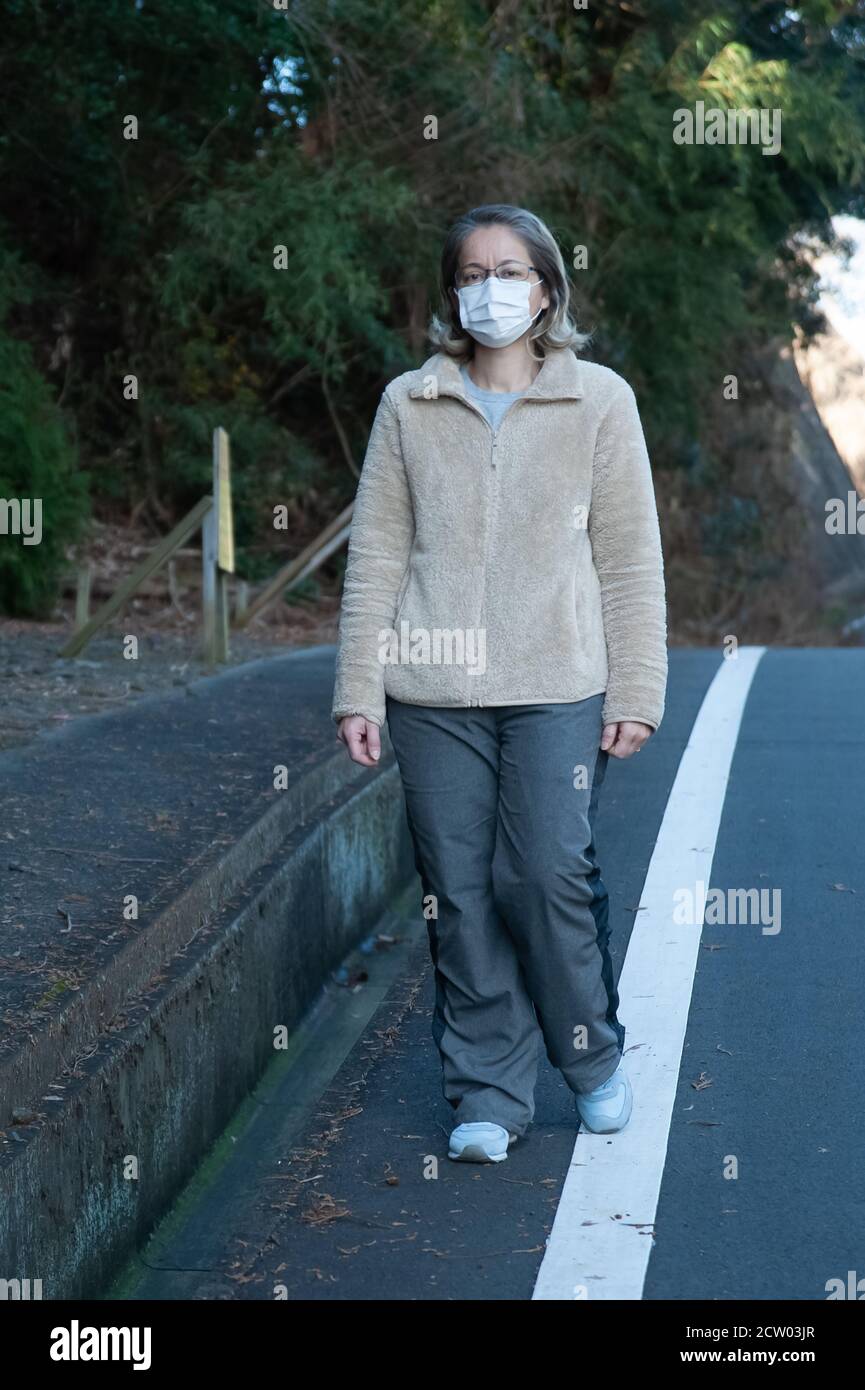 Frau 40-49 Jahre alt im Freien mit Brille und weißer Maske zum Schutz gegen Coronavirus (COVID-19) und andere ansteckende Krankheiten. Stockfoto