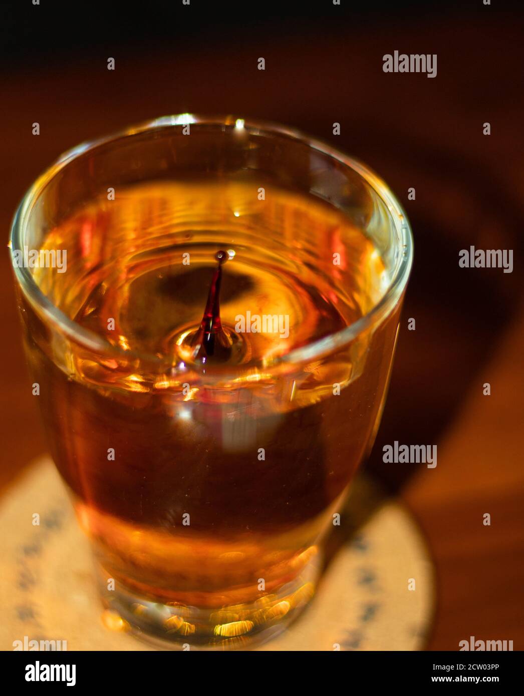Spritzer von roten Tropfen in einem Glas Wasser Stockfoto