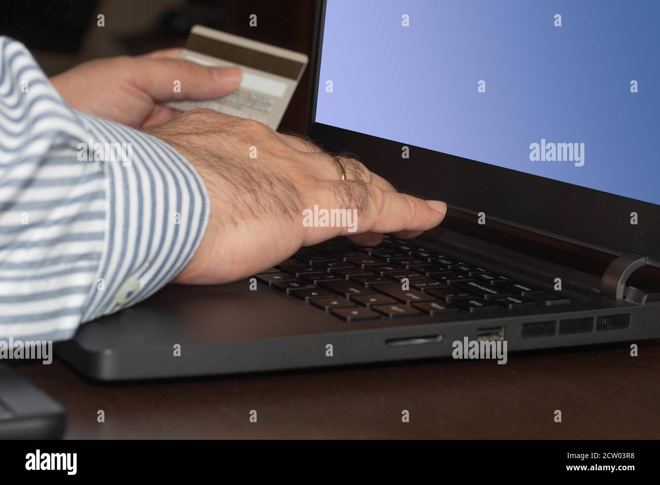 Geschäftsmann Eingabe von Bankkartendaten in den Laptop-Computer, um einen Online-Kauf auf einem Holztisch zu machen Stockfoto