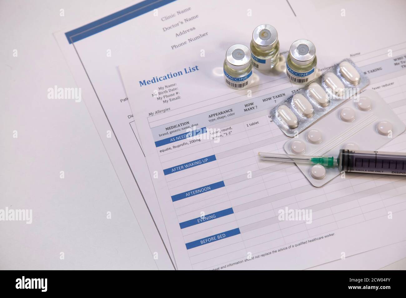 Injektionsspritze mit Impfstoffflaschen und Tabletten zusammen mit dem Patienten Medikamentenliste auf weißem Hintergrund Stockfoto