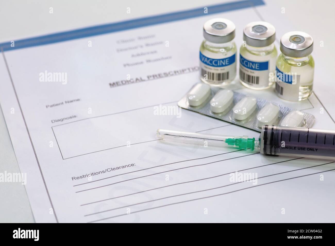Injektionsspritze mit Impfstoffflaschen und Tabletten zusammen mit dem Patienten Medikamentenliste auf weißem Hintergrund Stockfoto