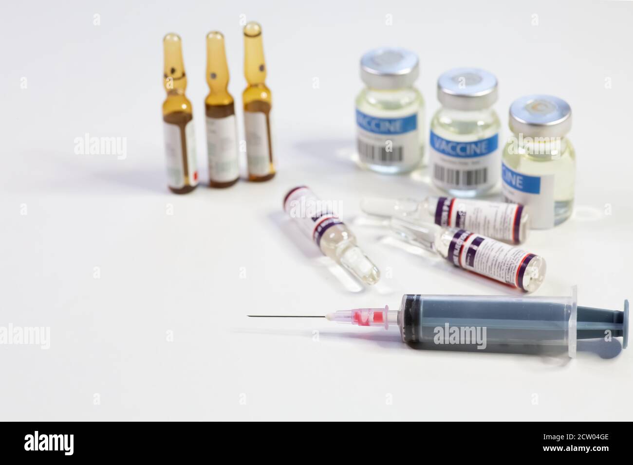 Hypodermische Spritzennadel mit Impfstoffflaschen und Injektionsfläschchen auf Weißer Hintergrund Stockfoto