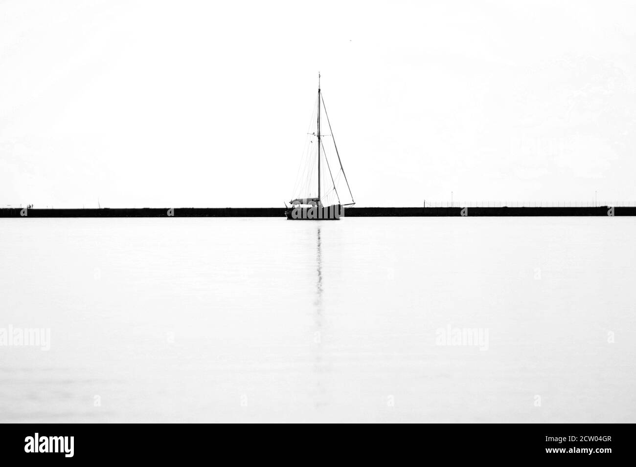 Segelboot mit Wasserspiegelung - schwarz-weiß Foto Stockfoto