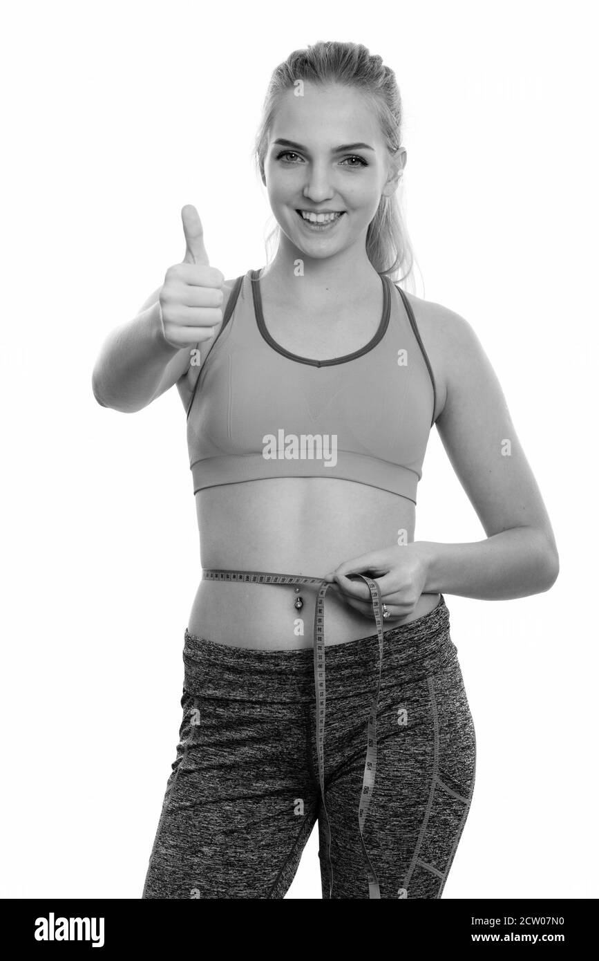 Studio shot Junger happy teenage Mädchen lächelnd während der Messung Taille und den Daumen nach oben bereit für Fitnessraum Stockfoto