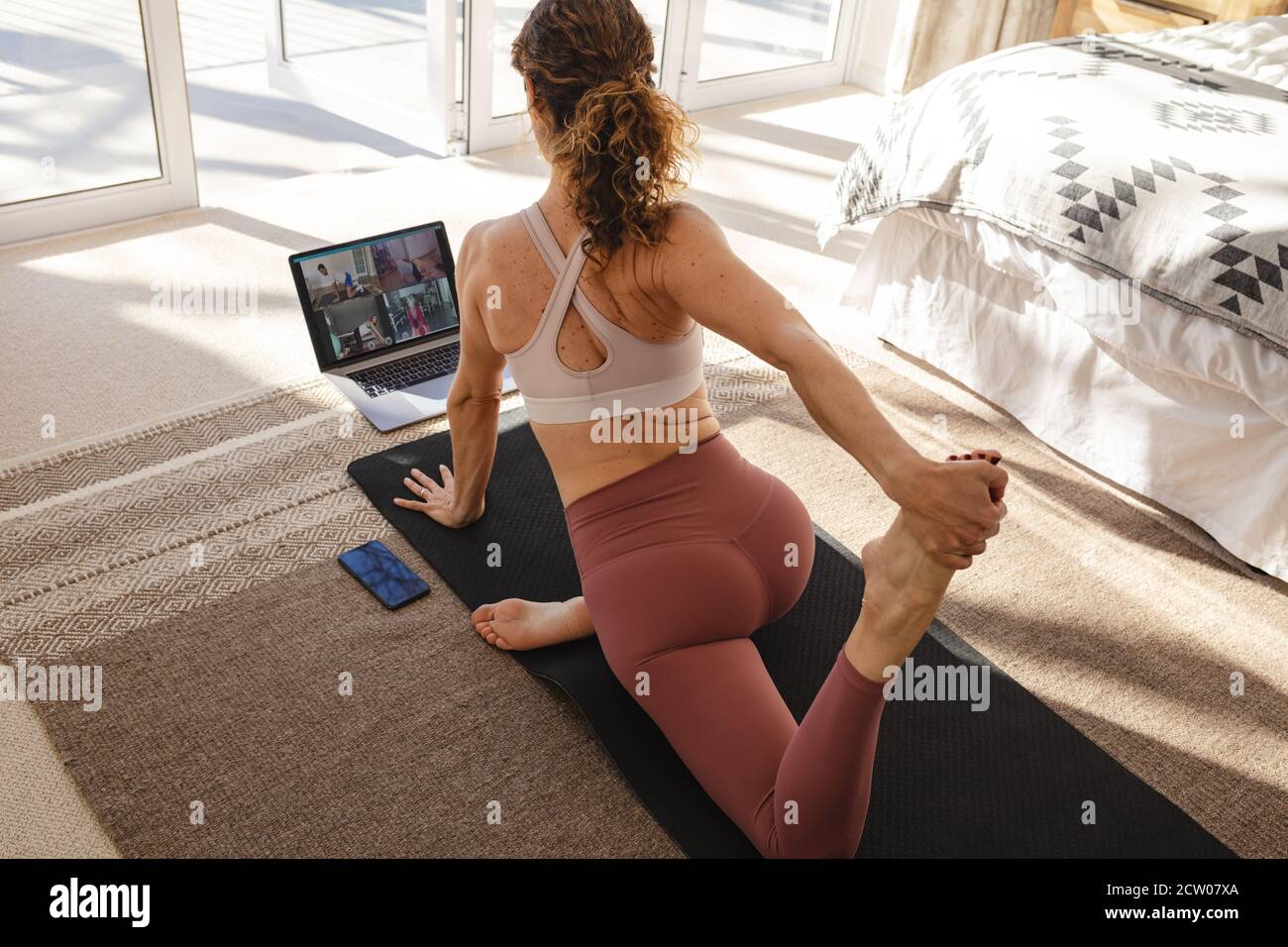 Frau, die Yoga online für eine Gruppe von Menschen von zu Hause unterrichtet. Yoga-Trainer demonstriert den Schülern Yoga-Posen per Videokonferenz. Stockfoto