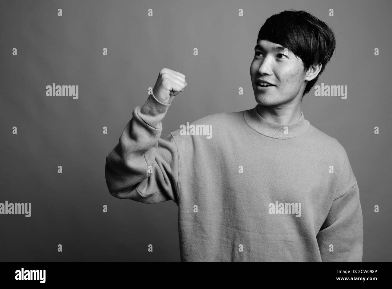 Junger asiatischer Mann mit Pullover auf grauem Hintergrund Stockfoto