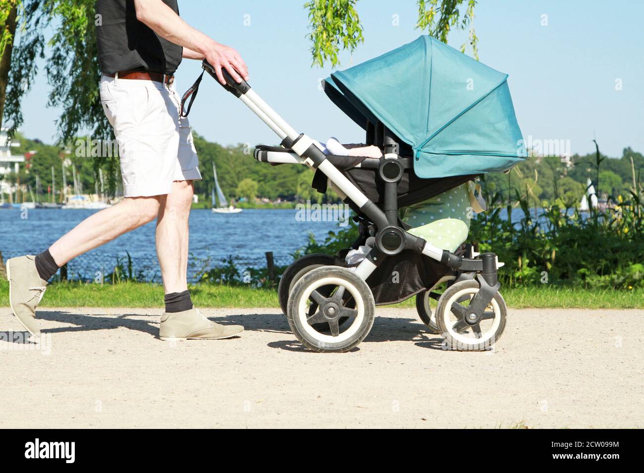 Vater schob den Kinderwagen auf der Fußstraße im Park Stockfoto