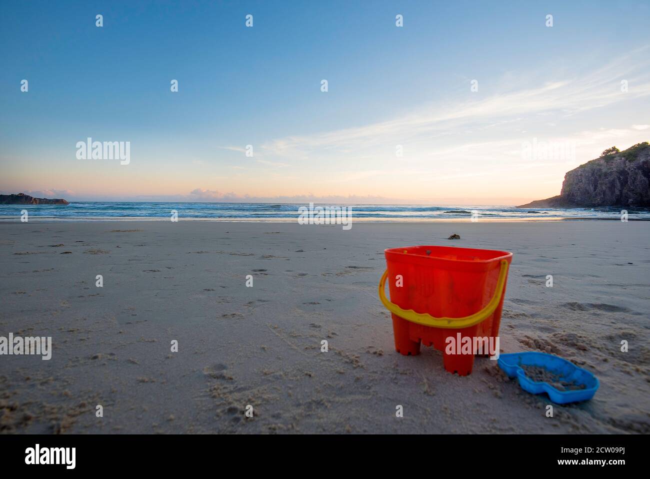 Verlassene Strandspielzeuge, die an einem leeren Strand zurückgelassen wurden, begrüßen den Sonnenaufgang am frühen Morgen eines Sommers in Little Beach, Scotts Head, New South Wales, Australien Stockfoto