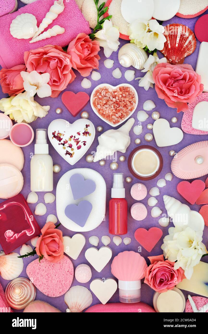 Naturheilbad Beauty-Behandlung Produkte mit Blumen und dekorative Muscheln und Perlen. Auf meliertem violettem Hintergrund. Stockfoto