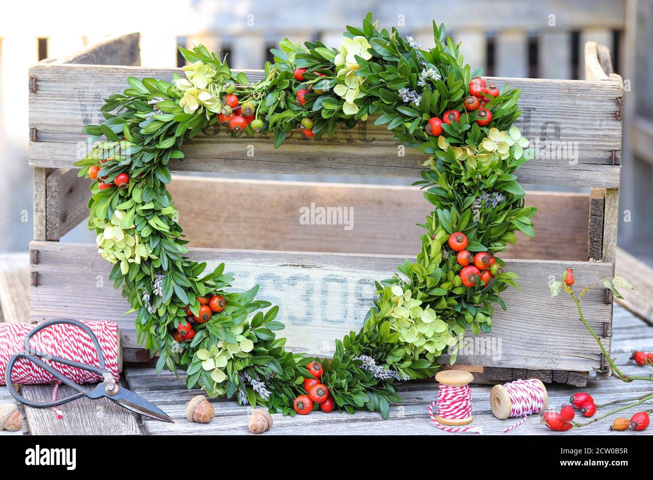 Romantische Dekoration mit Herz aus Hagebutten, Hortensien Blumen und Box Baum Äste Stockfoto