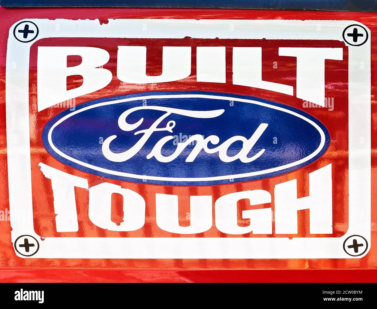 Bemalte Beschilderung eines Ford-Auto-Unternehmen Marke Logo auf einem roten Hintergrund, Ford gebaut hart, zeigt die Unterstützung für Qualität made Fahrzeuge, in Asien gesehen Stockfoto