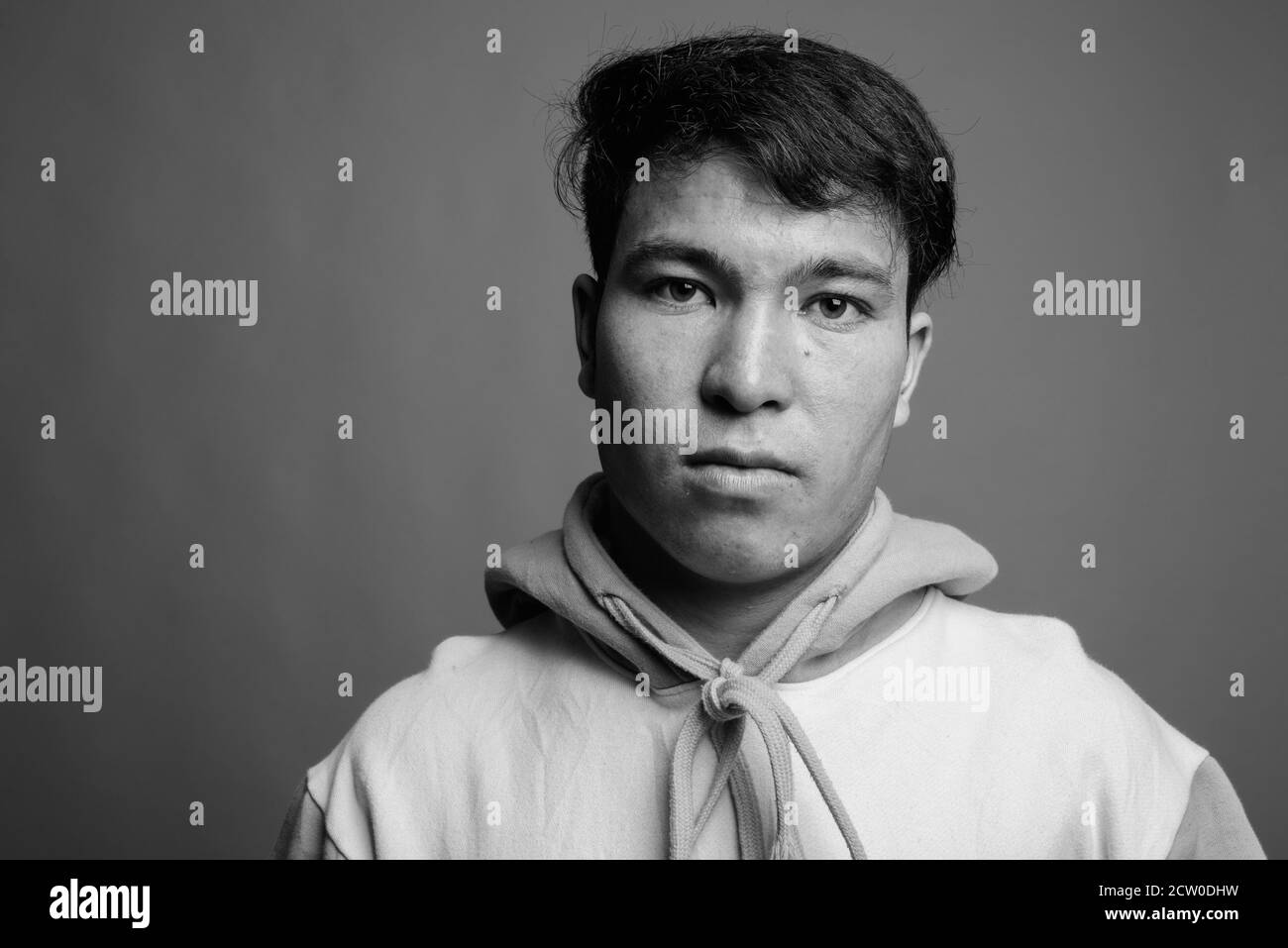 Jungen asiatischen Menschen tragen bunte Hoodie gegen grauer Hintergrund Stockfoto