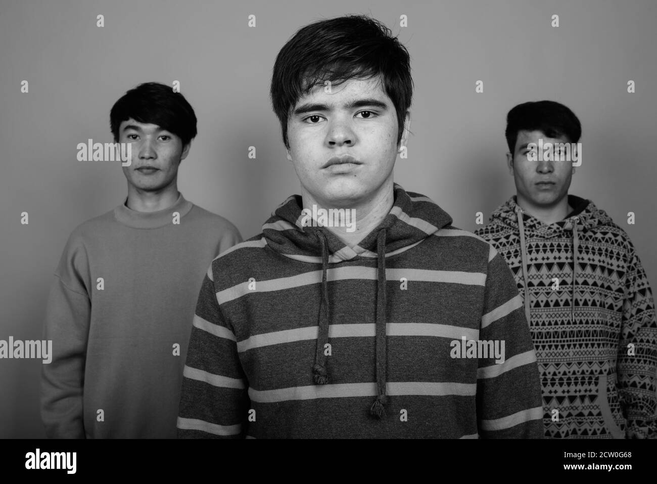 Drei jungen asiatischen Freunden gemeinsam gegen grauer Hintergrund Stockfoto