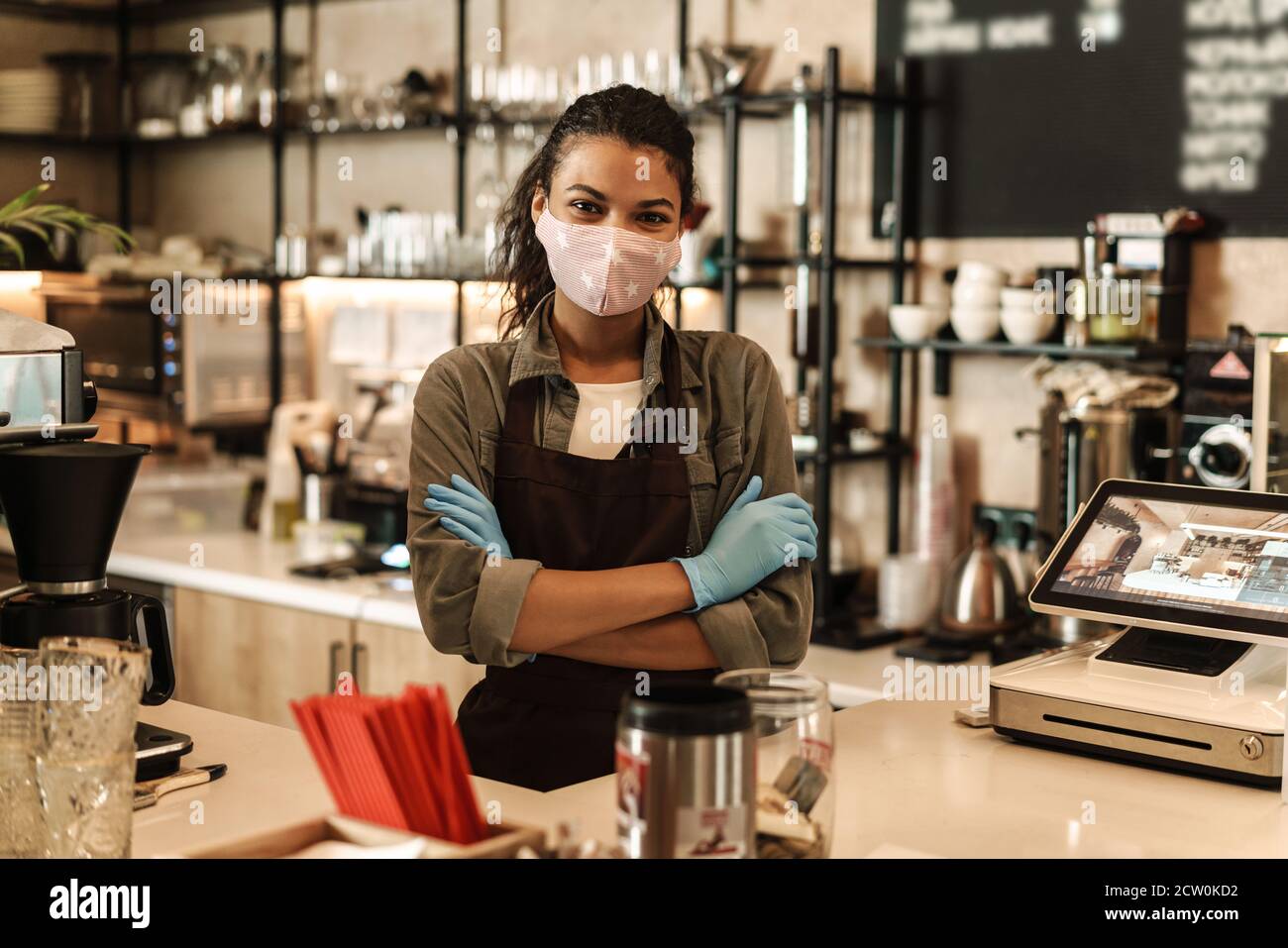 Frau mit Gesichtsmaske steht an der Theke, Shop nach dem Lockdown geöffnet Stockfoto
