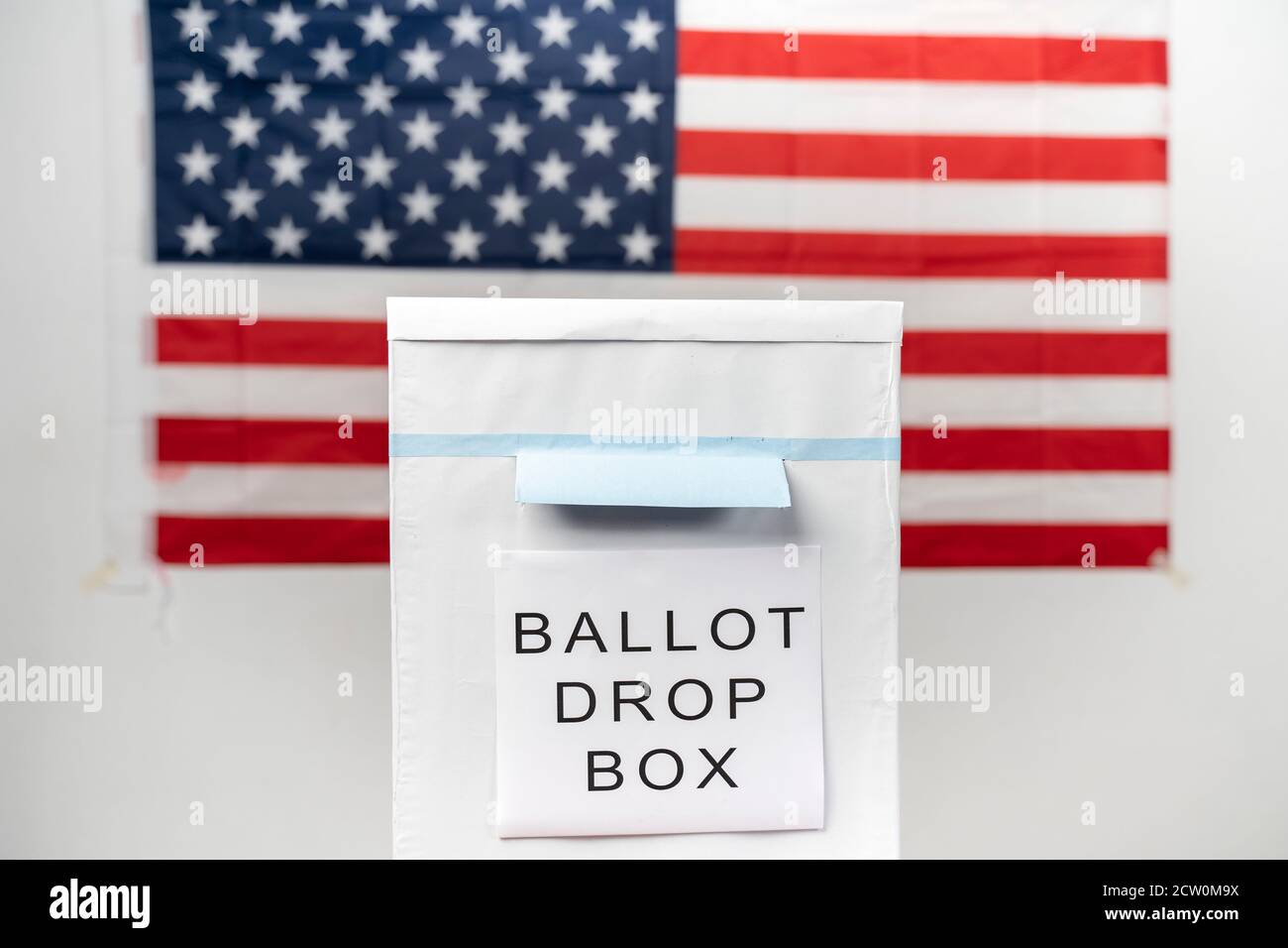 Konzept der Mail in Abstimmung an US-Wahlurne mit US-Flagge als Hintergrund. Stockfoto