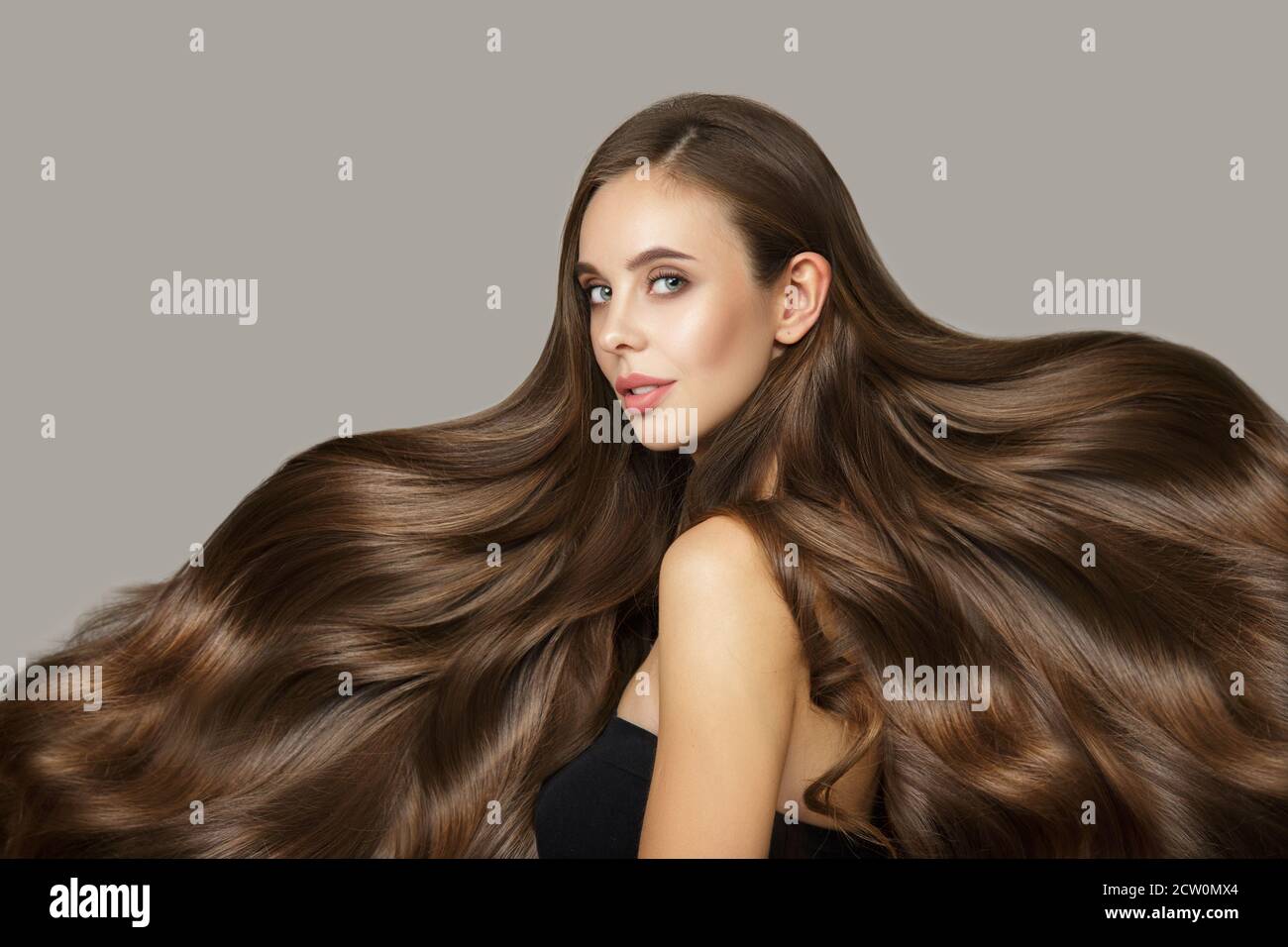 Brunette Frau Mit Glanzenden Welligen Haaren Junge Mode Madchen Mit Haaren Flattern Im Wind Luxus Glanzendes Haar Auf Grauem Hintergrund Stockfotografie Alamy