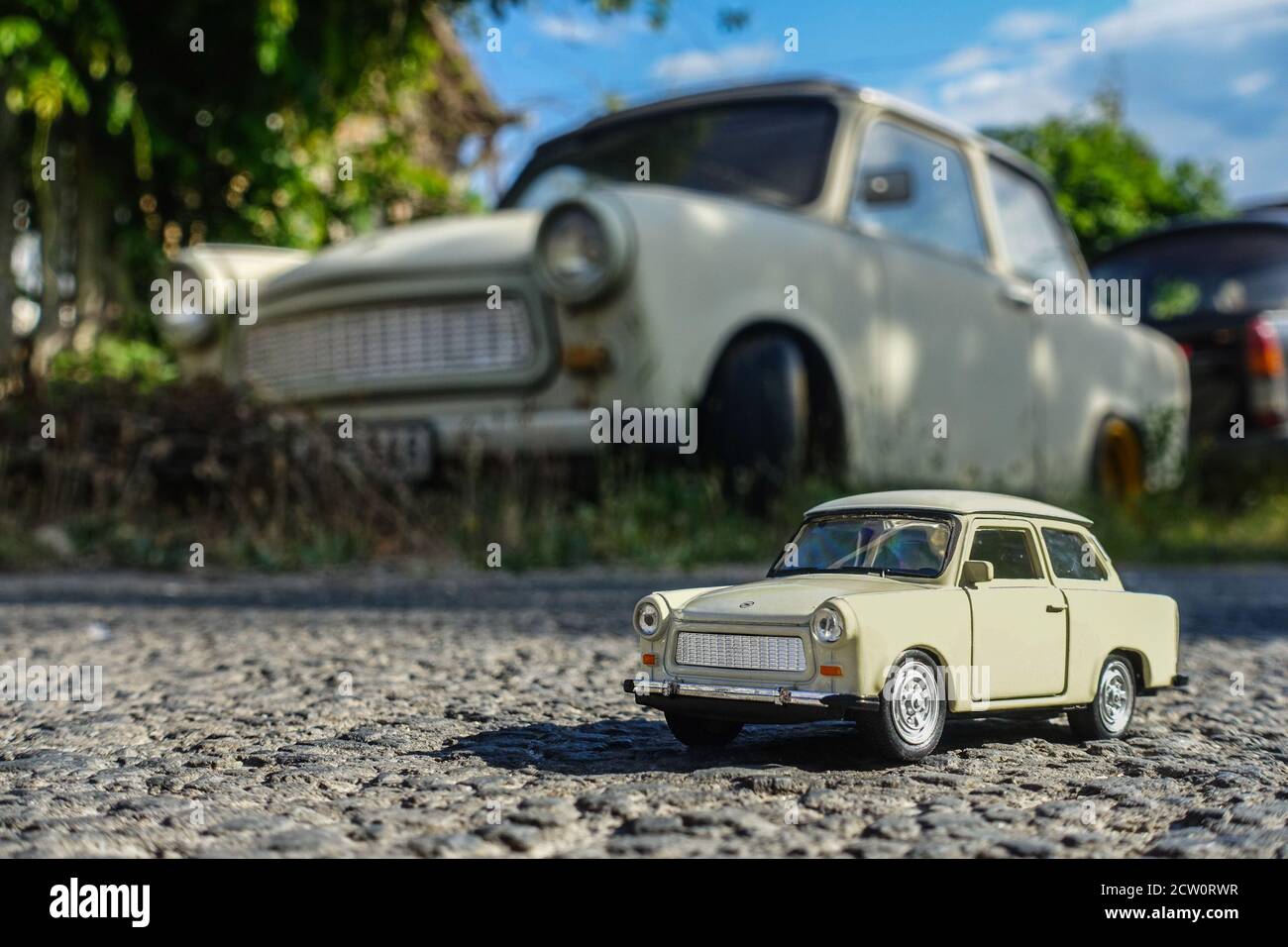 Spielzeug Trabant mit einem echten im Hintergrund Tapete, deutsche Retro-Auto-Tapete Stockfoto