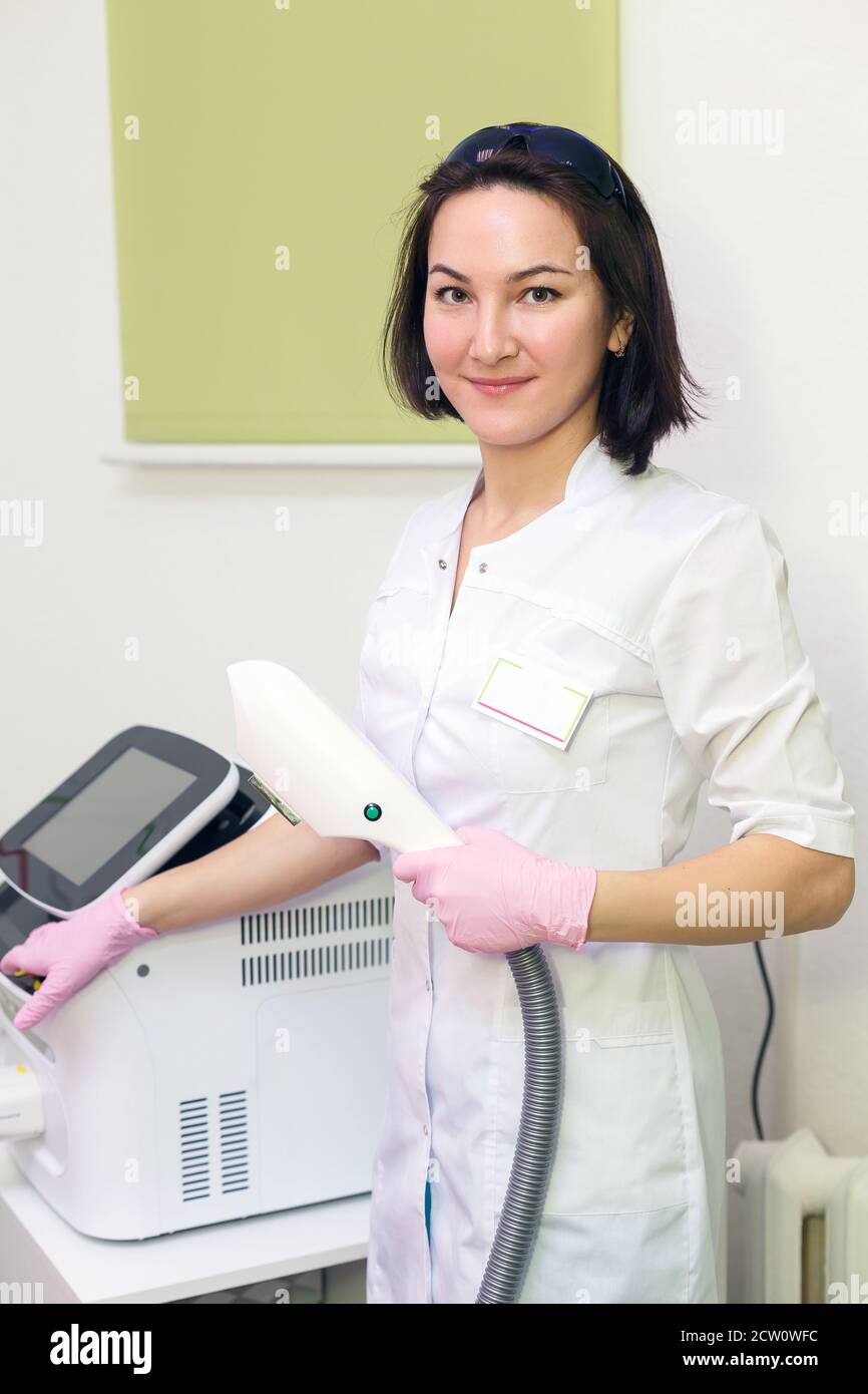 Junge Frau Meister der Entfernung von Laserhaaren, Laser getrennt, Frau lächelt. Haarentfernung im Bereich Kosmetologie Stockfoto