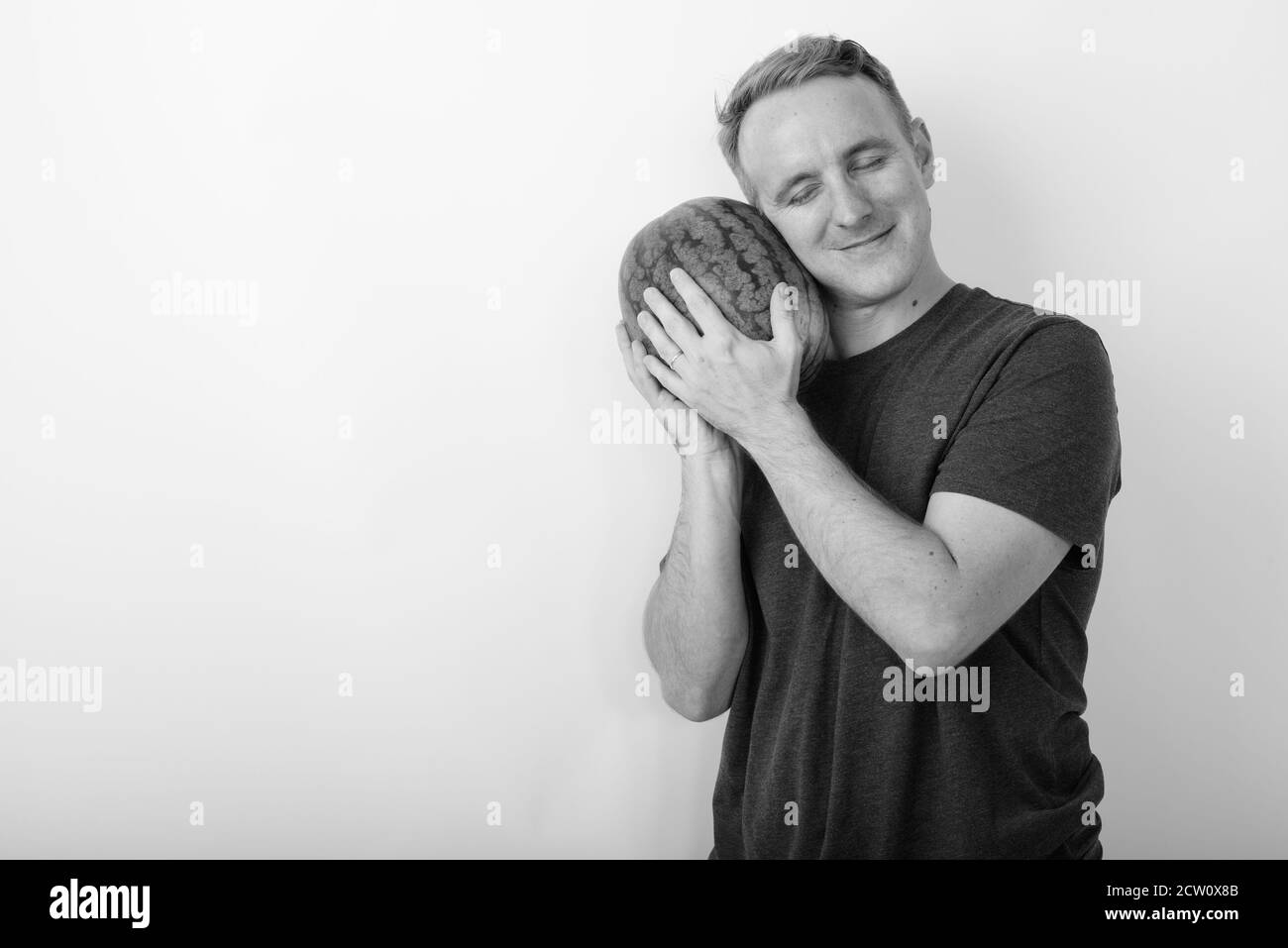 Studio shot Junger stattlicher Mann mit Wassermelone als Baby mit Augen vor weißem Hintergrund geschlossen Stockfoto