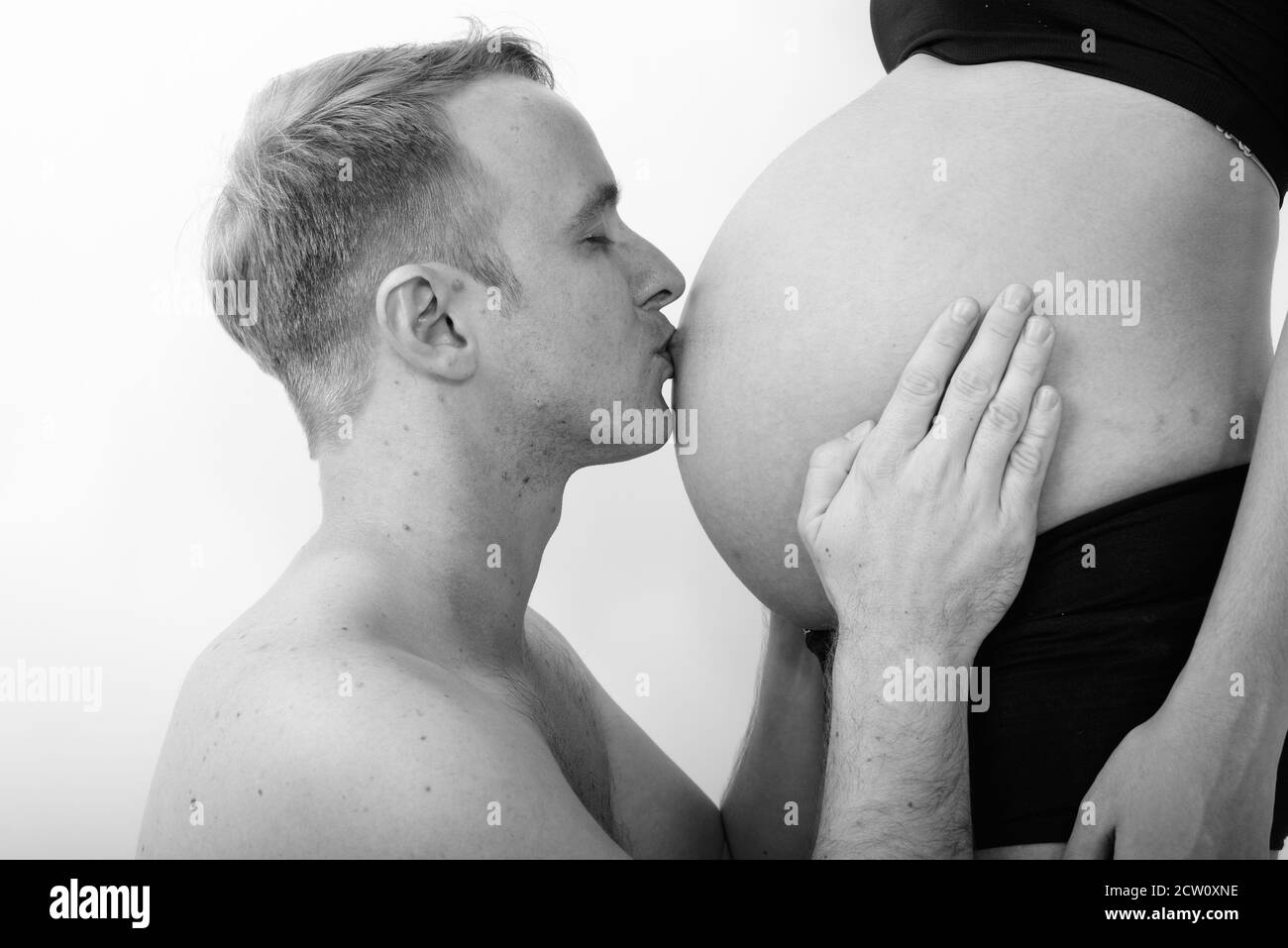 Profil anzeigen von jungen Mann küssen den Bauch seiner Frau mit Liebe zum Baby gegen den weißen Hintergrund Stockfoto