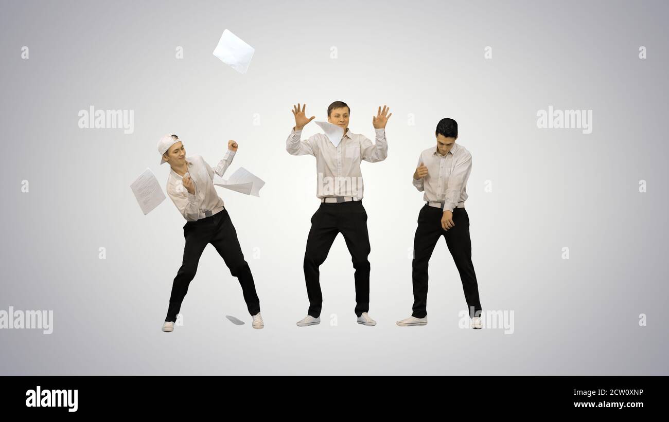 Drei Jungs werfen Dokumente in die Luft und beginnen zu Dance i Stockfoto
