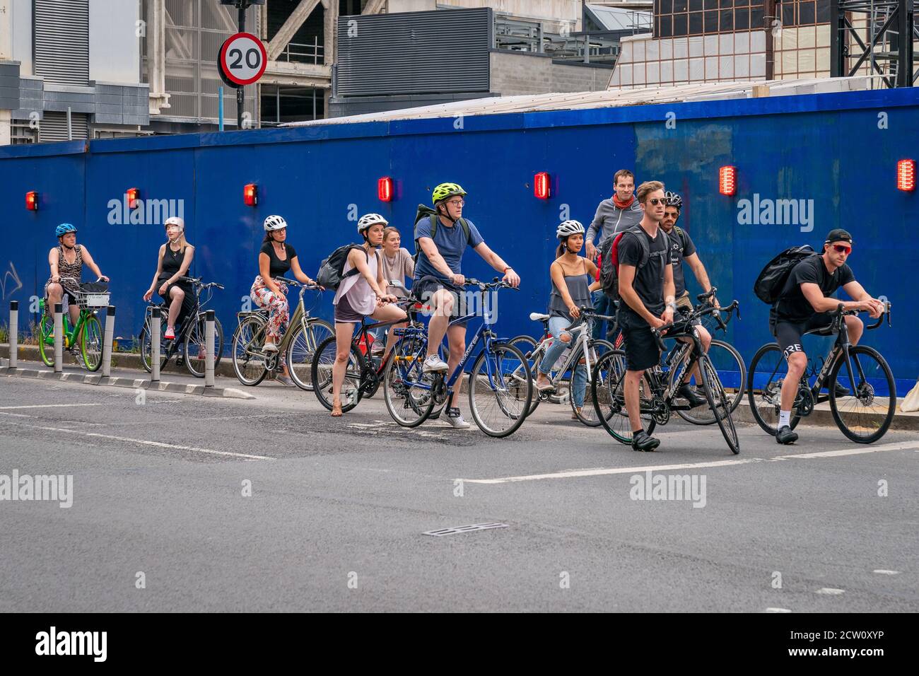 LONDON, ENGLAND - 24. JULI 2020: Eine Gruppe von Pendlerfahrern mit Sturzhelmen wartet an der Ampel auf einer Fahrradautobahn in Farrindon, Lond Stockfoto