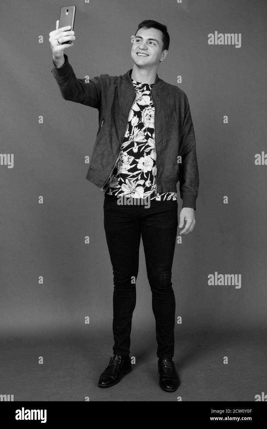 Studio shot Junger stattlicher Mann gegen grauer Hintergrund Stockfoto