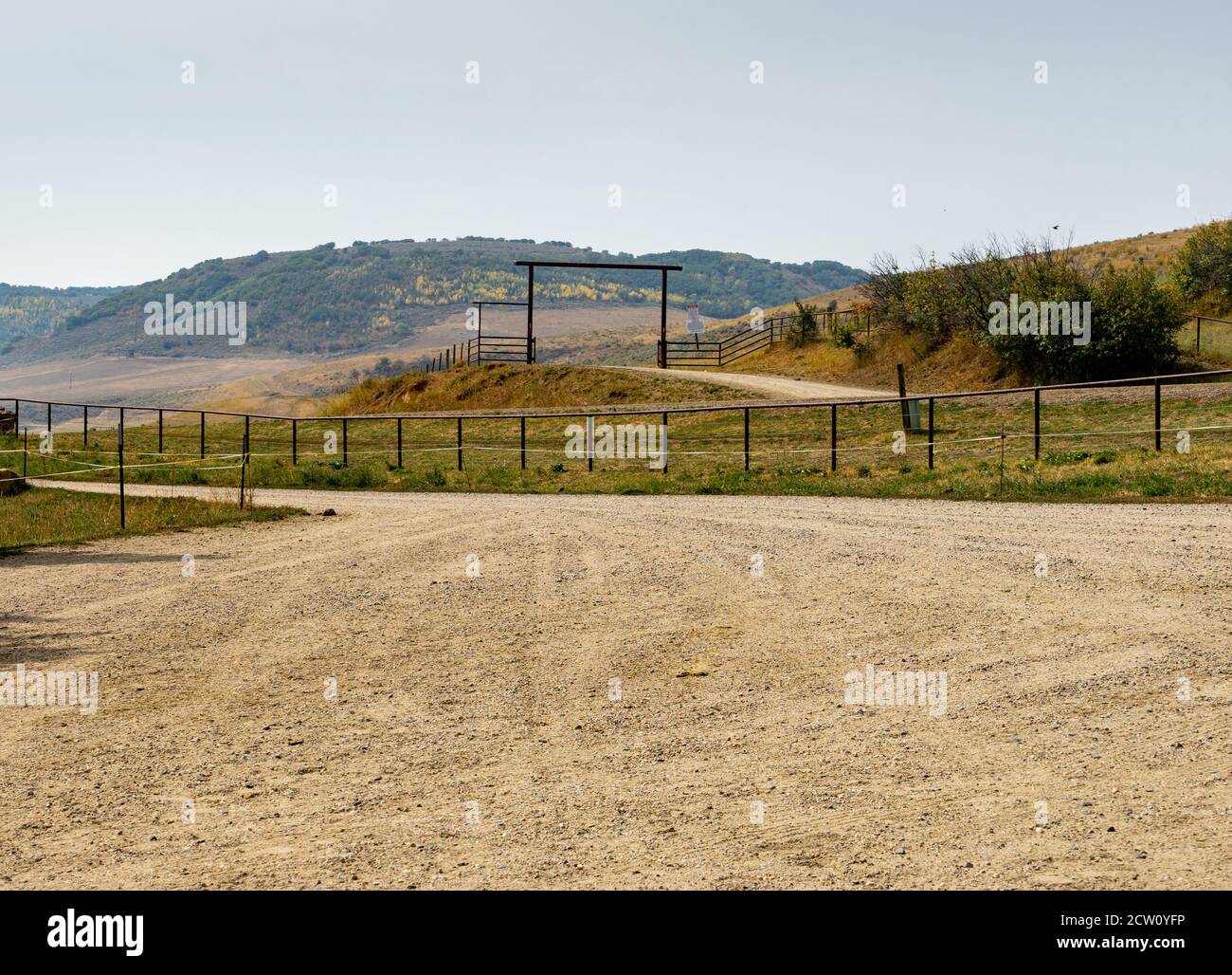 Große Schotterfläche mit Metallzaun und Bergen im Hintergrund. Stockfoto