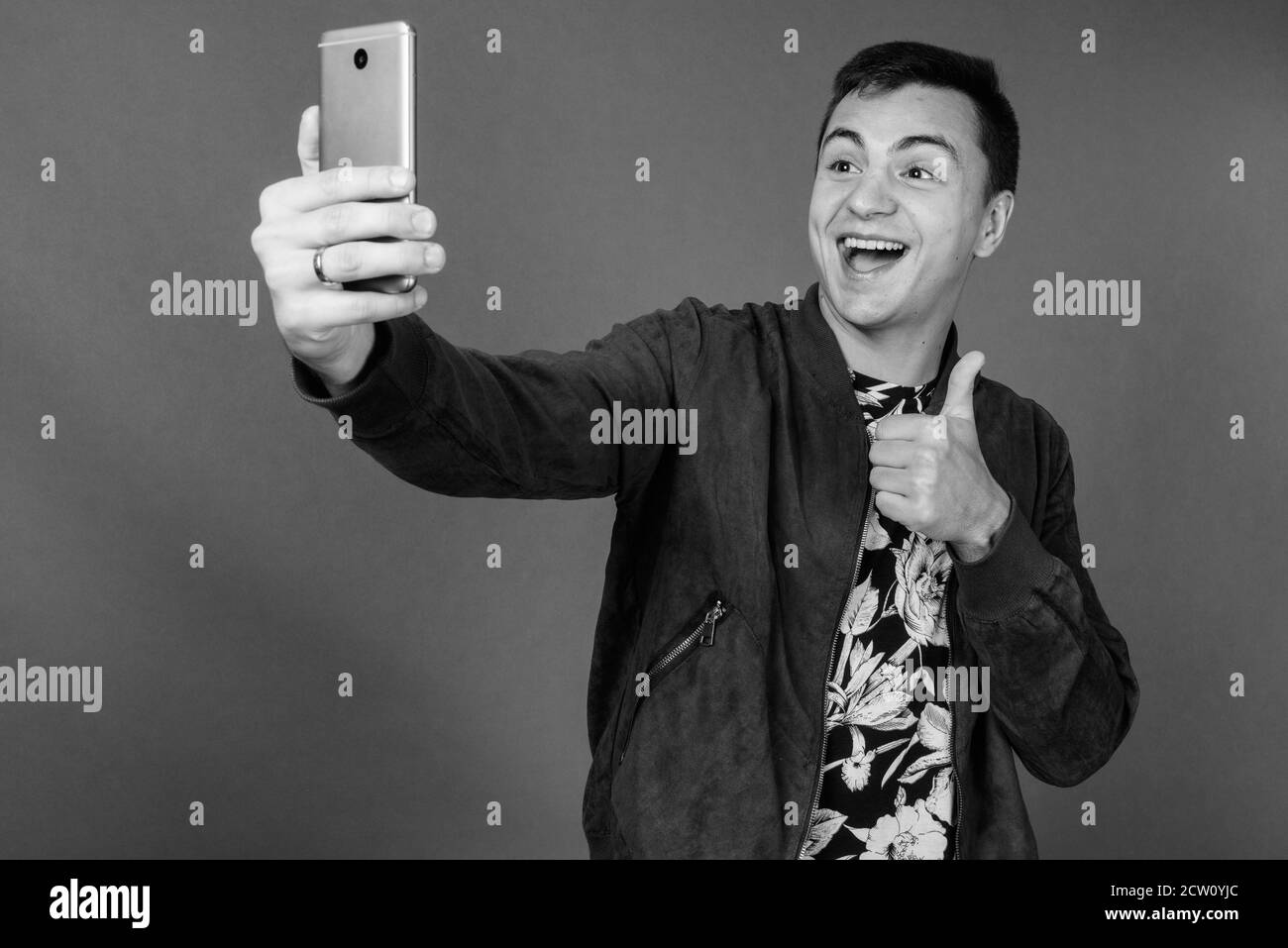 Studio shot Junger stattlicher Mann gegen grauer Hintergrund Stockfoto