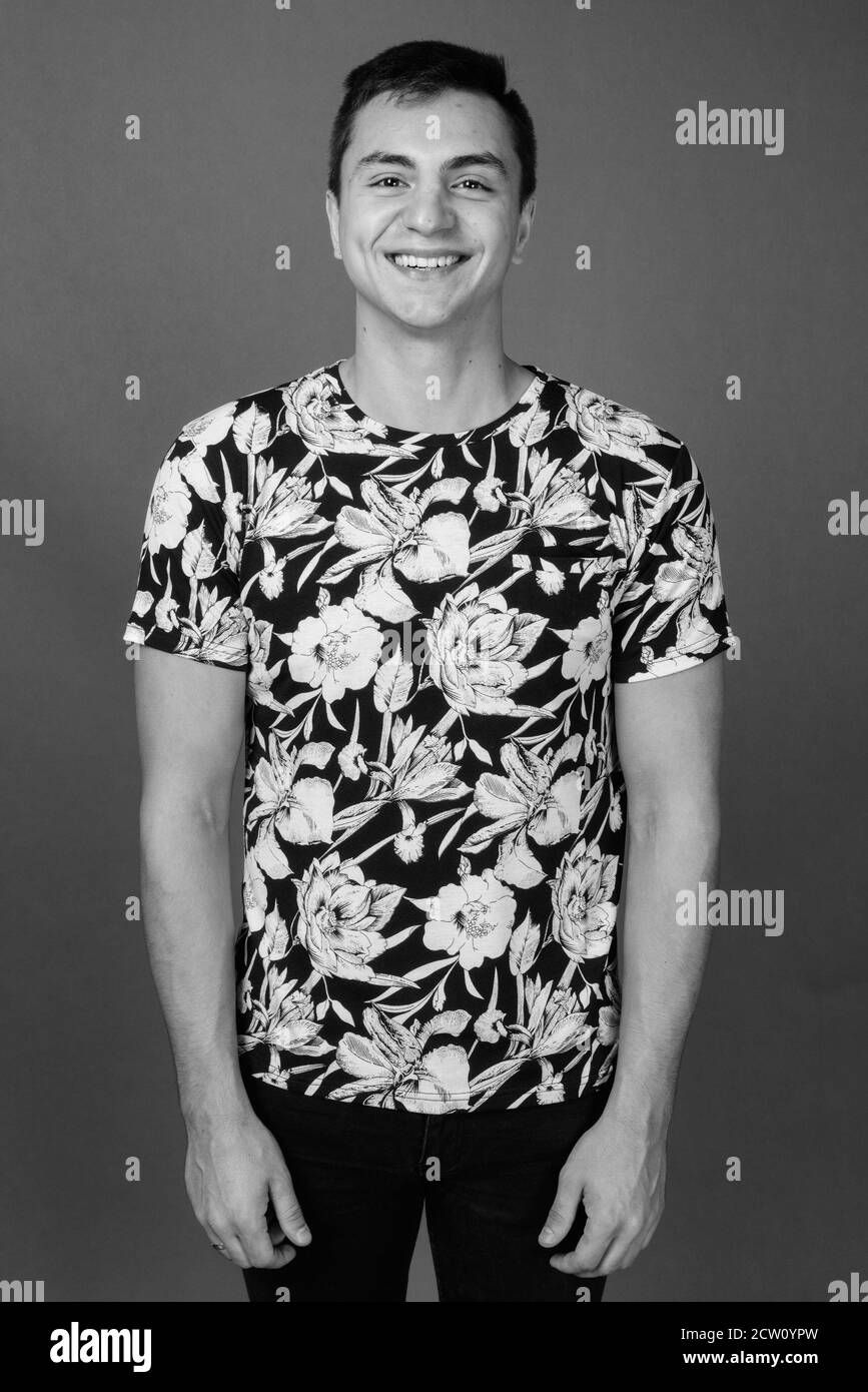 Studio shot Junger stattlicher Mann gegen grauer Hintergrund Stockfoto