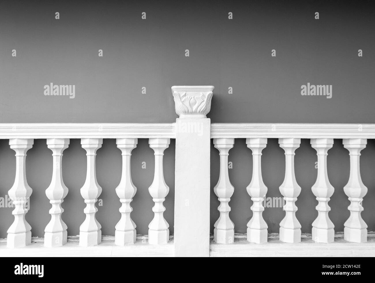 Weiße Steinsäule Zaun Balustrade gegenüber grauen Zementwand Stockfoto