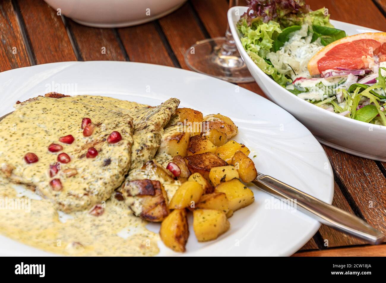 Schweineschnitzel mit Wein - Sahne - Kräuter - Sauce Mit Bratkartoffeln und gemischtem Salat Stockfoto
