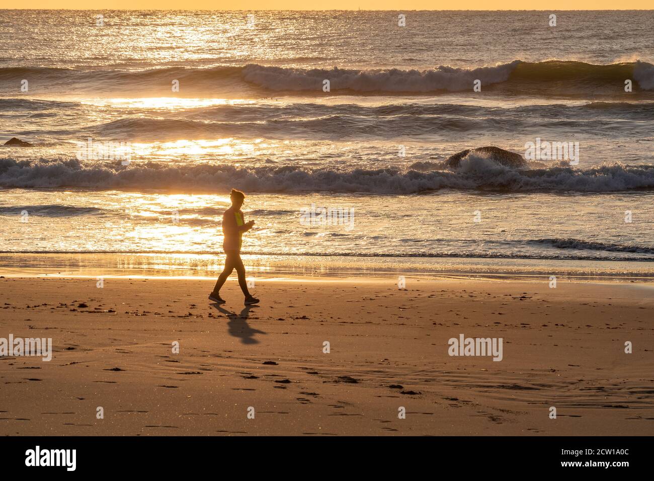 Frau, die am Strand mit dem Handy läuft und die wunderschöne Landschaft um sie herum ignoriert. Stockfoto
