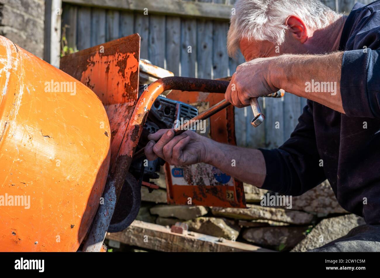 Senior Male Befestigung Cerment Mischer Gurt durch Einstellung Spannung von Riemen, um ein Verrutschen zu verhindern Stockfoto