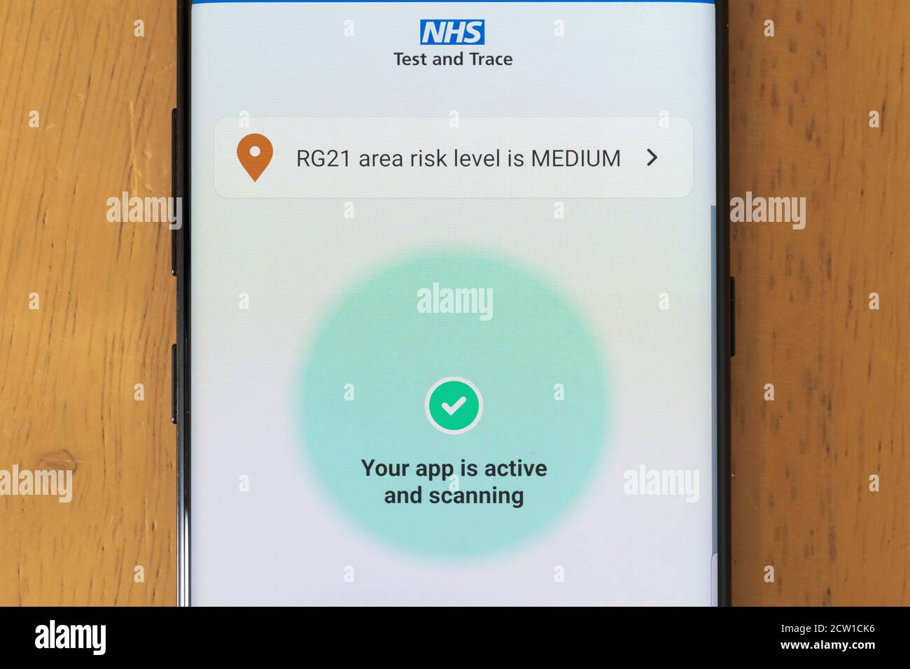 Die NHS Test und Trace App auf einem Smartphone-Bildschirm aktiv und Scannen zeigt das Risiko für ein Gebiet in England, Großbritannien Stockfoto