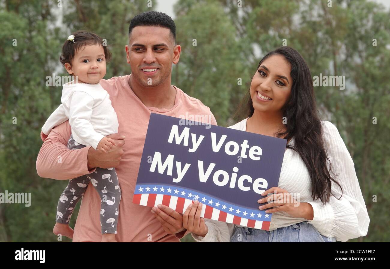Eine junge Latino-Familie hält ein Stimmschild und Lächelt für die Kamera Stockfoto