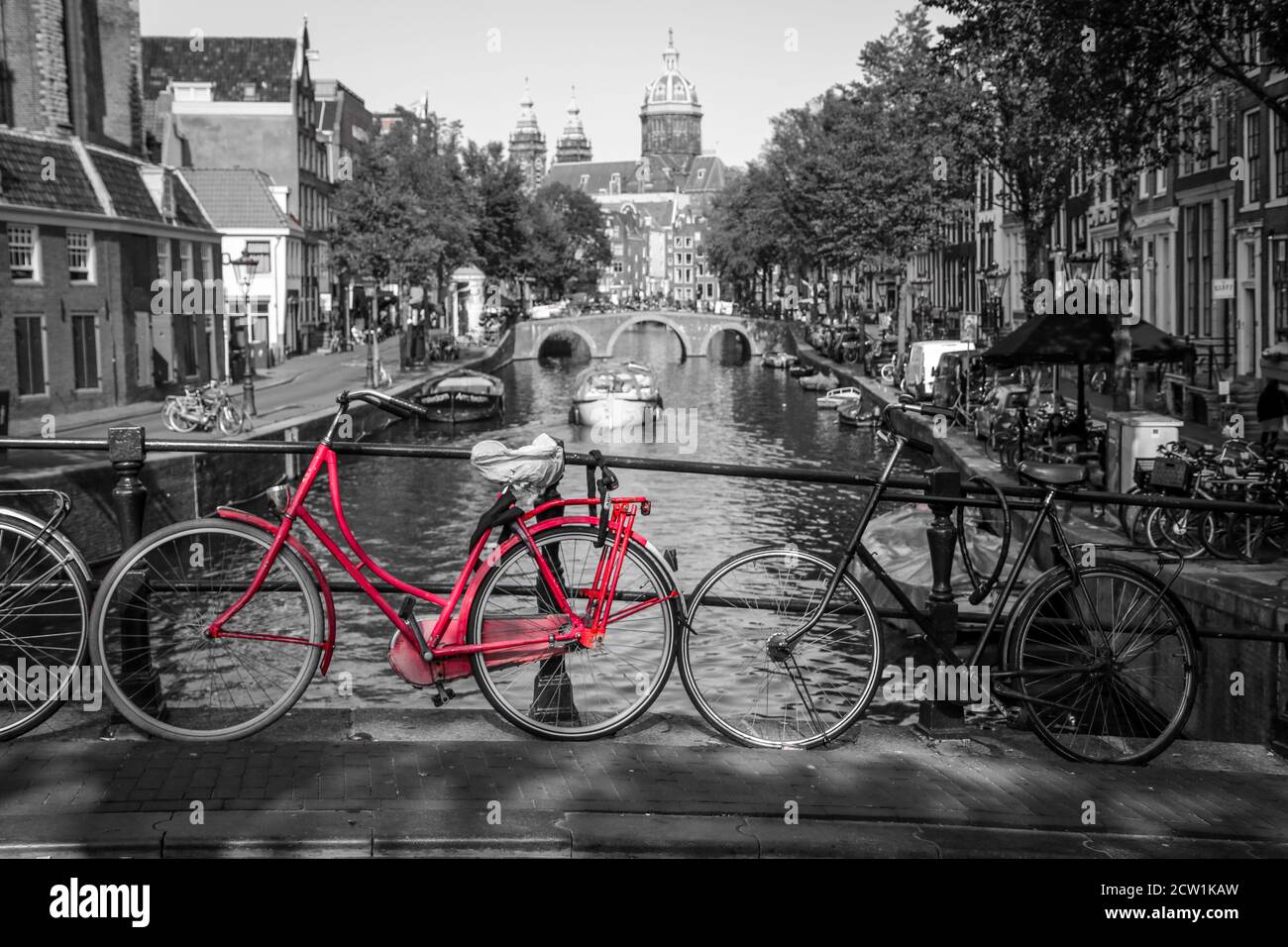 Ein Bild von einem roten Fahrrad auf der Brücke über den Kanal in Amsterdam.  Der Hintergrund ist schwarz-weiß Stockfotografie - Alamy