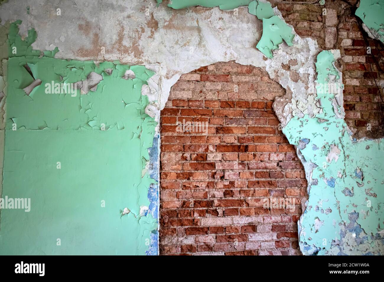 Alte verlassene Ziegelwand mit rissigem Putz und Farbe überzogen, grunge Hintergrund Stockfoto