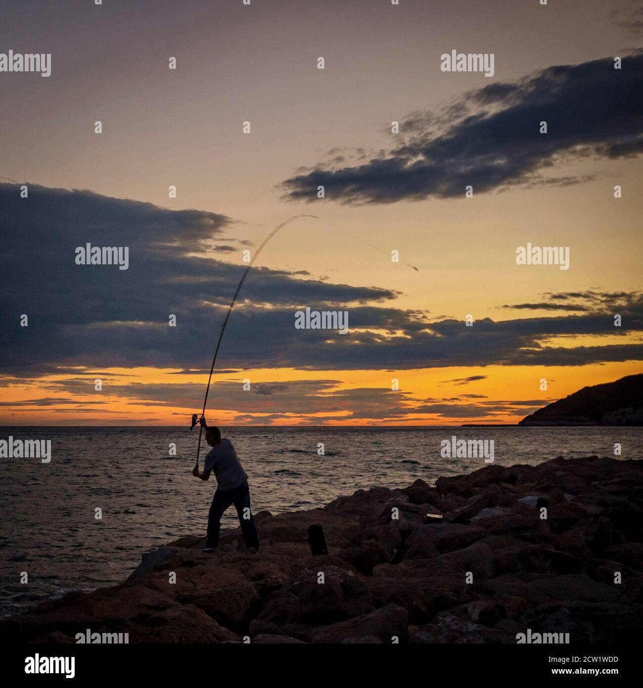 Ein Fischer wirft seine Angelrute aus dem Garraf Wellenbrecher, südlich von Barcelona, Katalonien, Spanien. Stockfoto