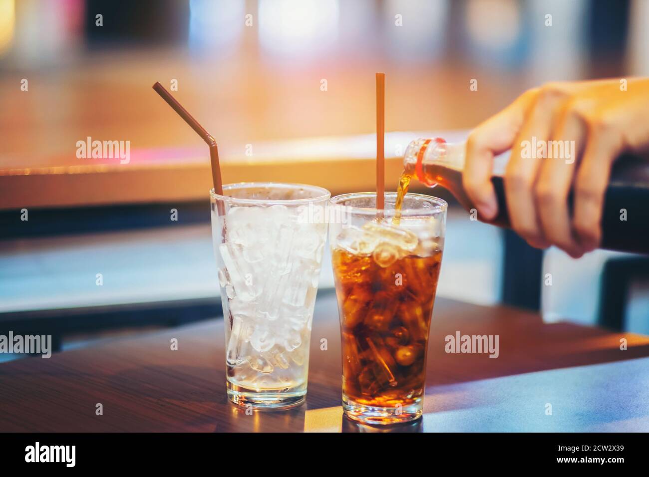 Glas Cola spritzt mit Eis auf Holztisch Hintergrund Stockfoto