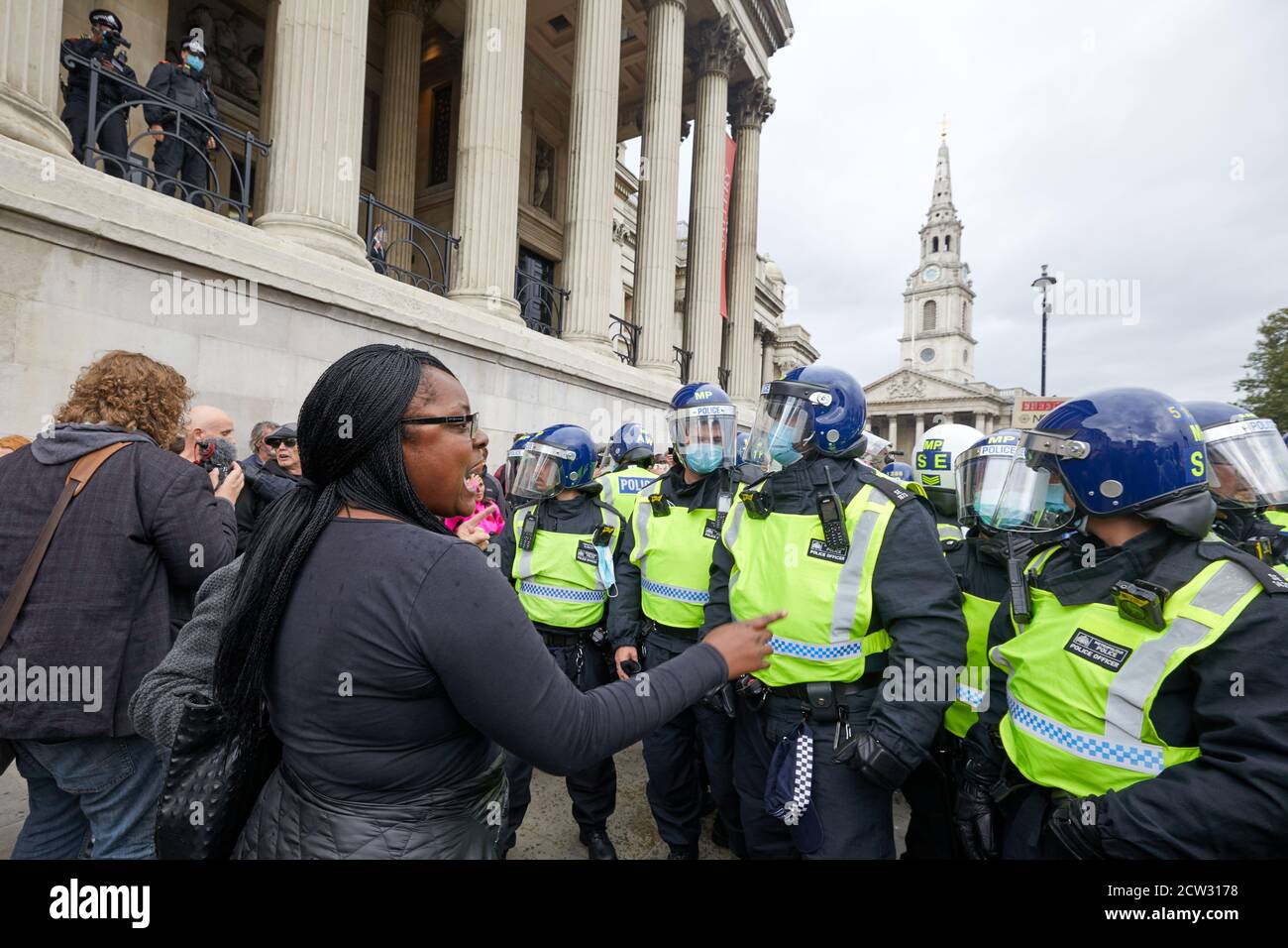 London, Großbritannien. - 26. September 2020: Ein Protestant remonstriert mit der Polizei bei einem Protest auf dem Trafalgar Square gegen die Beschränkungen des Coronavirus unter dem wachsamen Auge einer Überwachungseinheit oben. Stockfoto