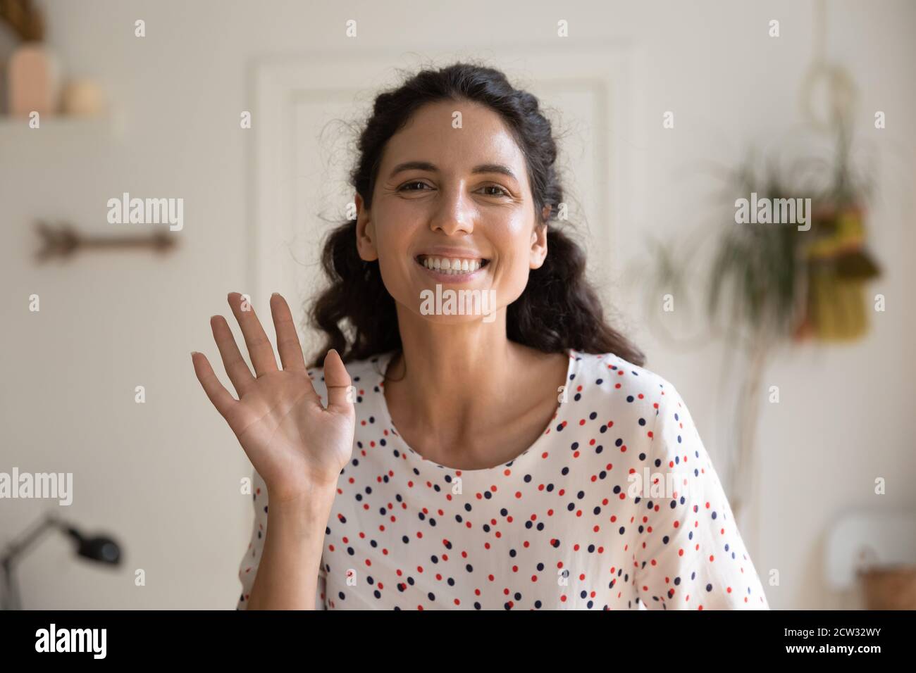 Headshot der glücklichen jungen Frau Blick auf Kamera winken Stockfoto